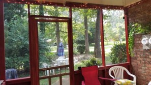 Eine überdachte Terrasse mit großen Fenstern mit Blick auf einen Garten.