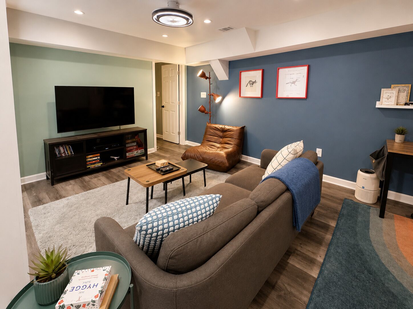 Un salon avec un canapé, une table basse, un téléviseur, une lampe et des tableaux encadrés accrochés au mur.