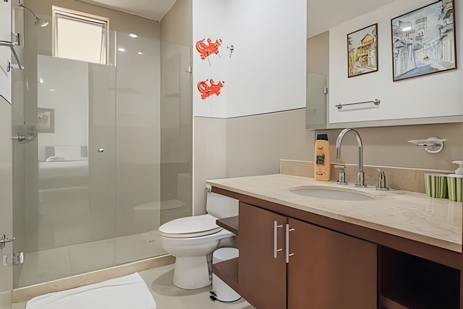 A modern bathroom with a glass shower enclosure, a toilet, a sink with a mirror, and a cabinet.
