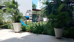 A playground with slides and climbing structures, surrounded by potted plants and a building in the background. - Premium Apartment at Morros Vitri (Cartagena)