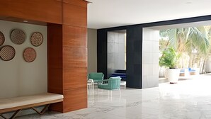 A modern lobby with a bench, a green chair, a white sofa, and a wall with circular patterns. - Premium Apartment at Morros Vitri (Cartagena)