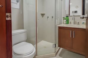 A bathroom with a toilet, a glass shower enclosure, and a sink with a cabinet. - Premium Apartment at Morros Vitri (Cartagena)