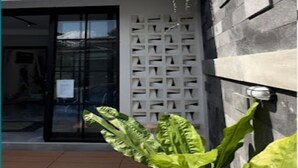 A building entrance with a glass door, a white decorative wall, and a potted plant. - Cozzy Penny House Private Pool (BATU)