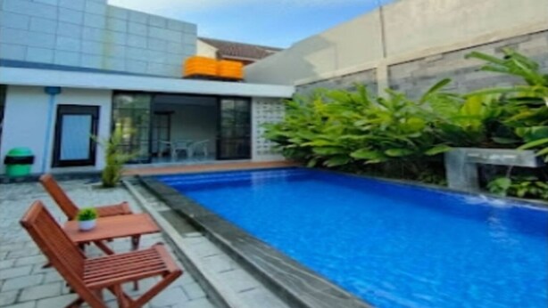 A modern building with a swimming pool, outdoor seating, and greenery. - Cozzy Penny House Private Pool (BATU)