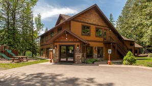 A lodge with a prominent entrance, a staircase, and a picnic area. - Escape to Ptarmigan Village 27 (Whitefish)