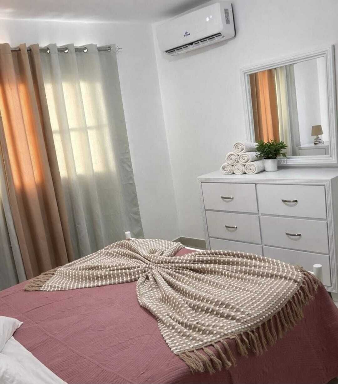 Une chambre à coucher comprenant un lit, une commode, un miroir et un appareil de climatisation.