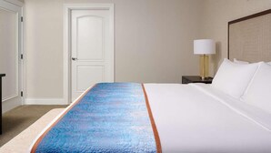 Une chambre d’hôtel avec un lit, une table de chevet avec une lampe et une porte.