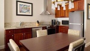 Une cuisine équipée d’une table à manger, de meubles en bois, d’appareils électroménagers en acier inoxydable et d’un luminaire suspendu.