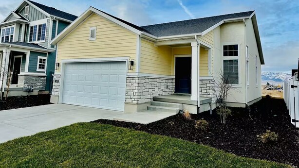 A two-story house with a garage, a stone foundation, and a front porch.