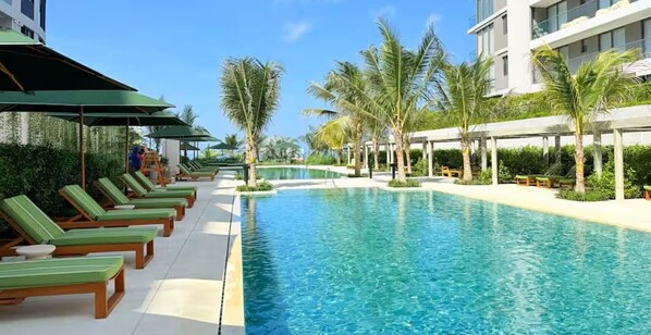 A swimming pool with lounge chairs and palm trees. - Apartment in Manzanillo, Cartagena, with direct beach access (Bolívar)