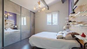 Ein Schlafzimmer mit einem großen Bett, einem Spiegel, einer Chandelier, einem Fenster und einem Regal mit Dekoration.