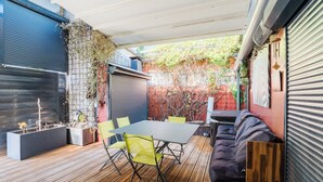 Eine überdachte Terrasse mit Tisch, Stühlen, einer Couch und Pflanzgefäßen mit Pflanzen.