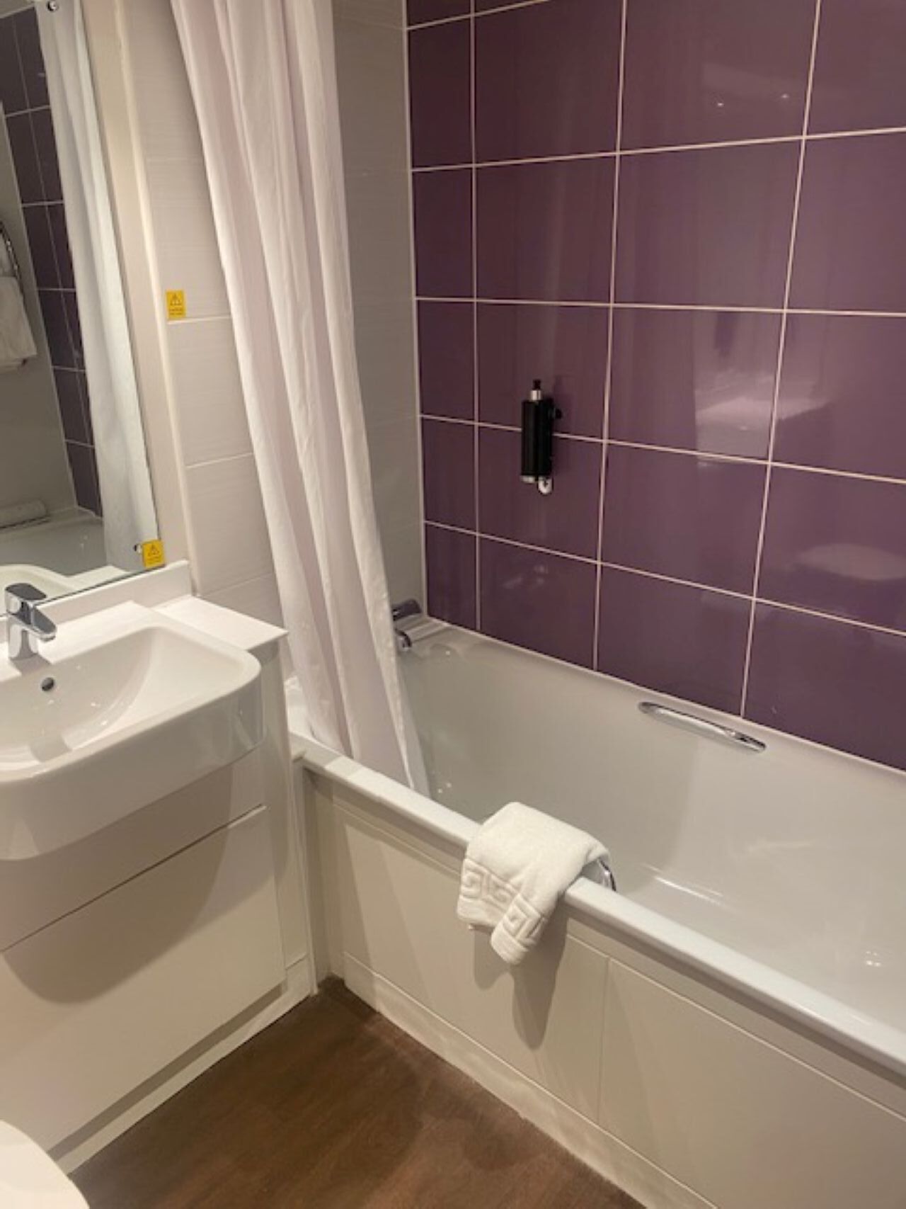 Een badkamer met een witte wastafel, een bad en een douchegordijn.