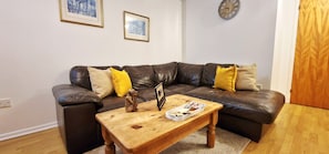 A living room with a leather sofa, a wooden coffee table, and two framed pictures on the wall.