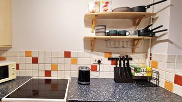 A kitchen with a microwave, a toaster, and a kettle on the counter.