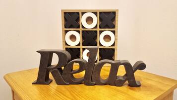 Una mesa de madera con la palabra 'Relax' en letras grandes. Detrás, un panel de madera muestra formas blancas y negras.