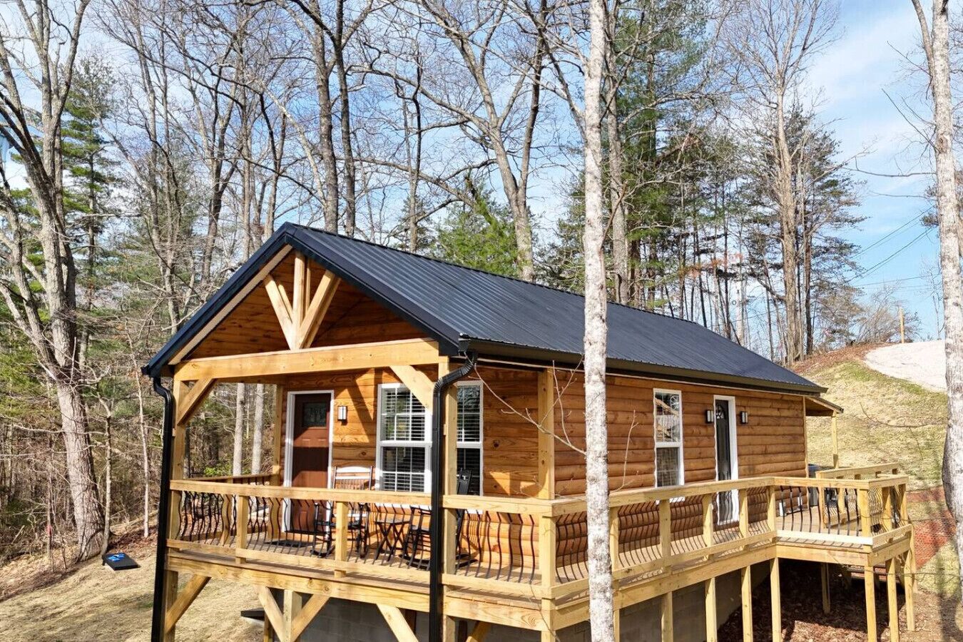 A wooden cabin with a balcony, surrounded by trees.