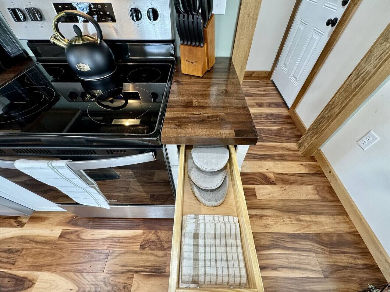A kitchen with a stove, a knife block, and a wooden countertop.