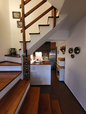 Eine Küche mit Holzboden, einer zentralen Kochinsel und einer Treppe, die in ein Obergeschoss führt.
