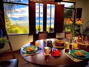 A dining table with breakfast items, a view of mountains, and a vase with flowers. - Finca Agrreste (Nemocón)