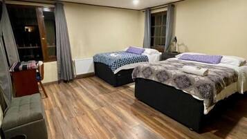 A room with two beds, a sofa, and a window with curtains.
