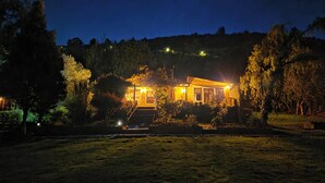 Uma casa com escadaria que leva à entrada, rodeada por árvores e um gramado.