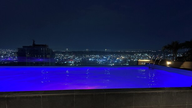 Una piscina en la azotea con vista a la ciudad de noche.