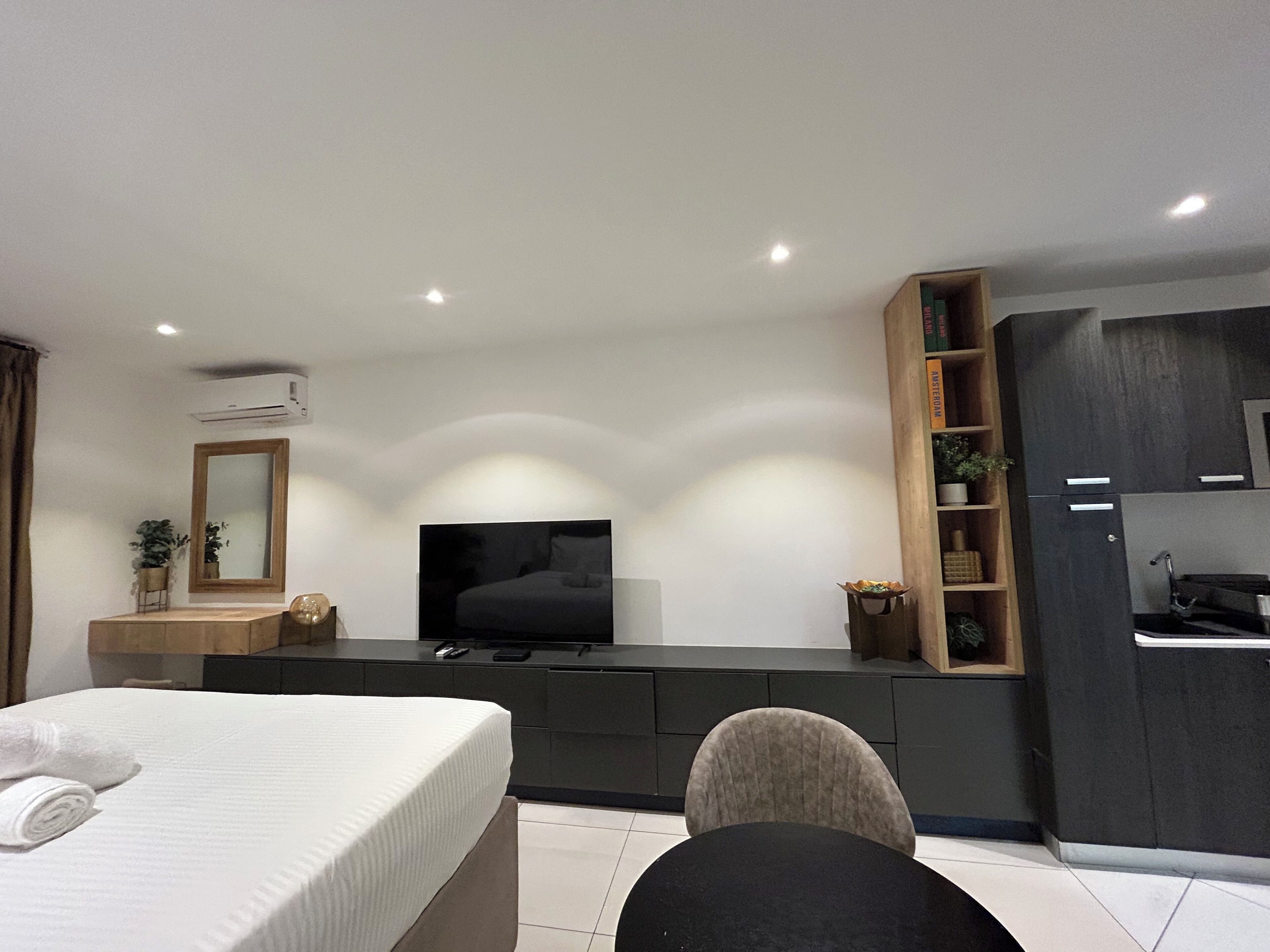 A modern bedroom with a bed, a TV, a desk, and a built-in wardrobe.