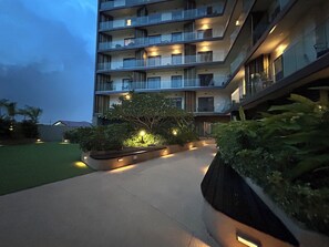 Ein mehrstöckiges Hotel mit Balkonen, einem angelegten Garten und einem Weg.