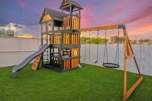 Un parque infantil con tobogán, columpios y una estructura para escalar.