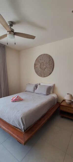 A bedroom with a bed, a ceiling fan, a wall-mounted decorative item, and a bedside table with a lamp. - Santa Akumalito (Tulum)