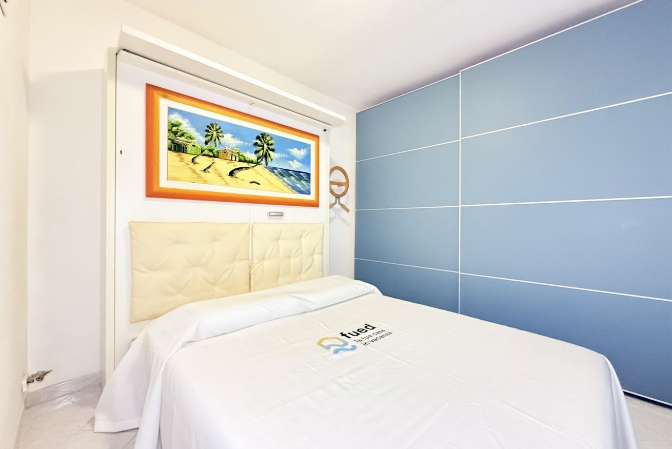 Quarto com uma cama, um quadro na parede e parede azul.