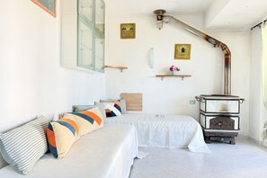 Une chambre avec deux lits, une armoire en bois, une étagère fixée au mur et une fenêtre donnant sur un beau paysage.