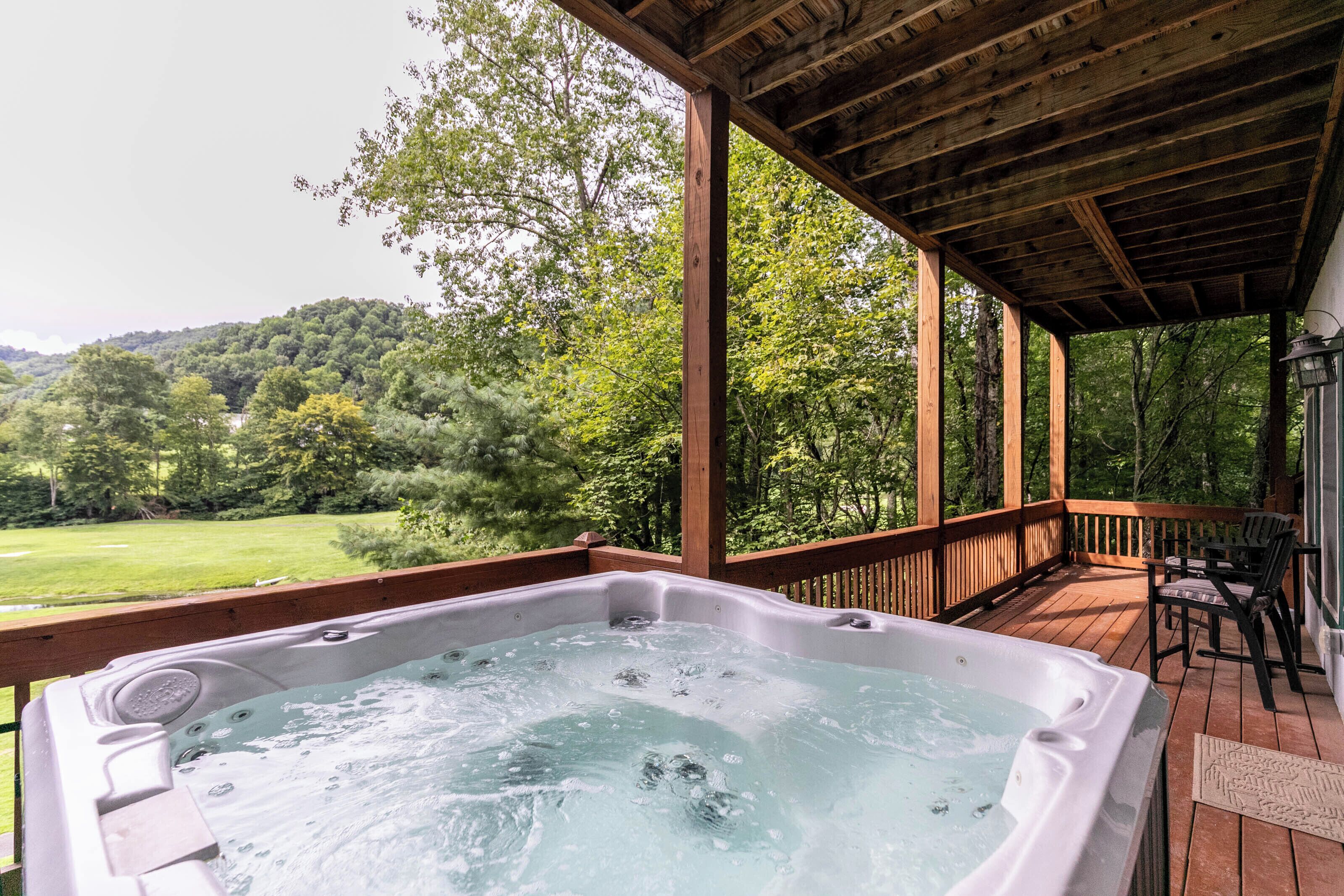 A hot tub on a wooden deck with a view of a forested area.