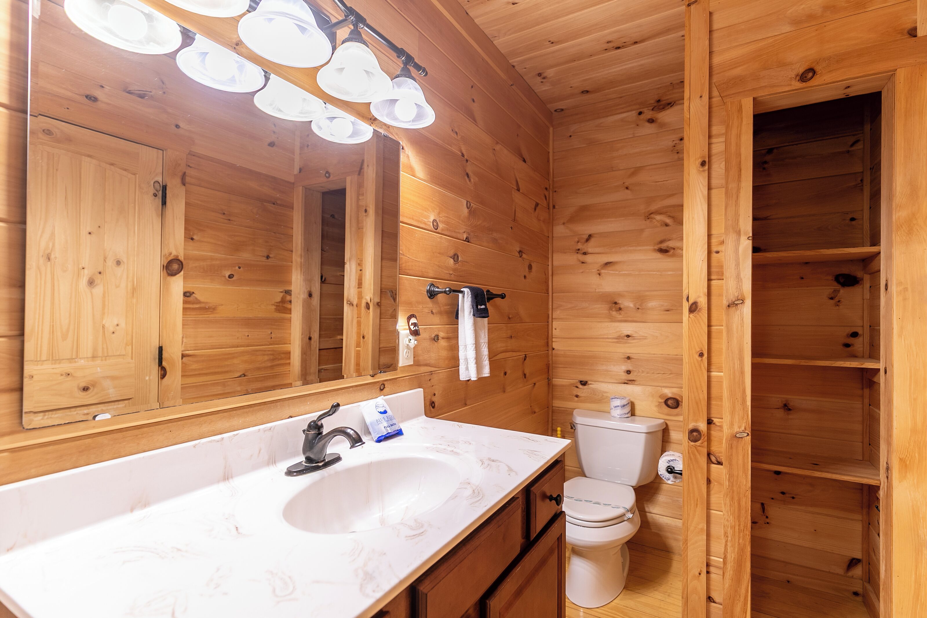 A wooden cabin bathroom with a sink, mirror, and toilet.