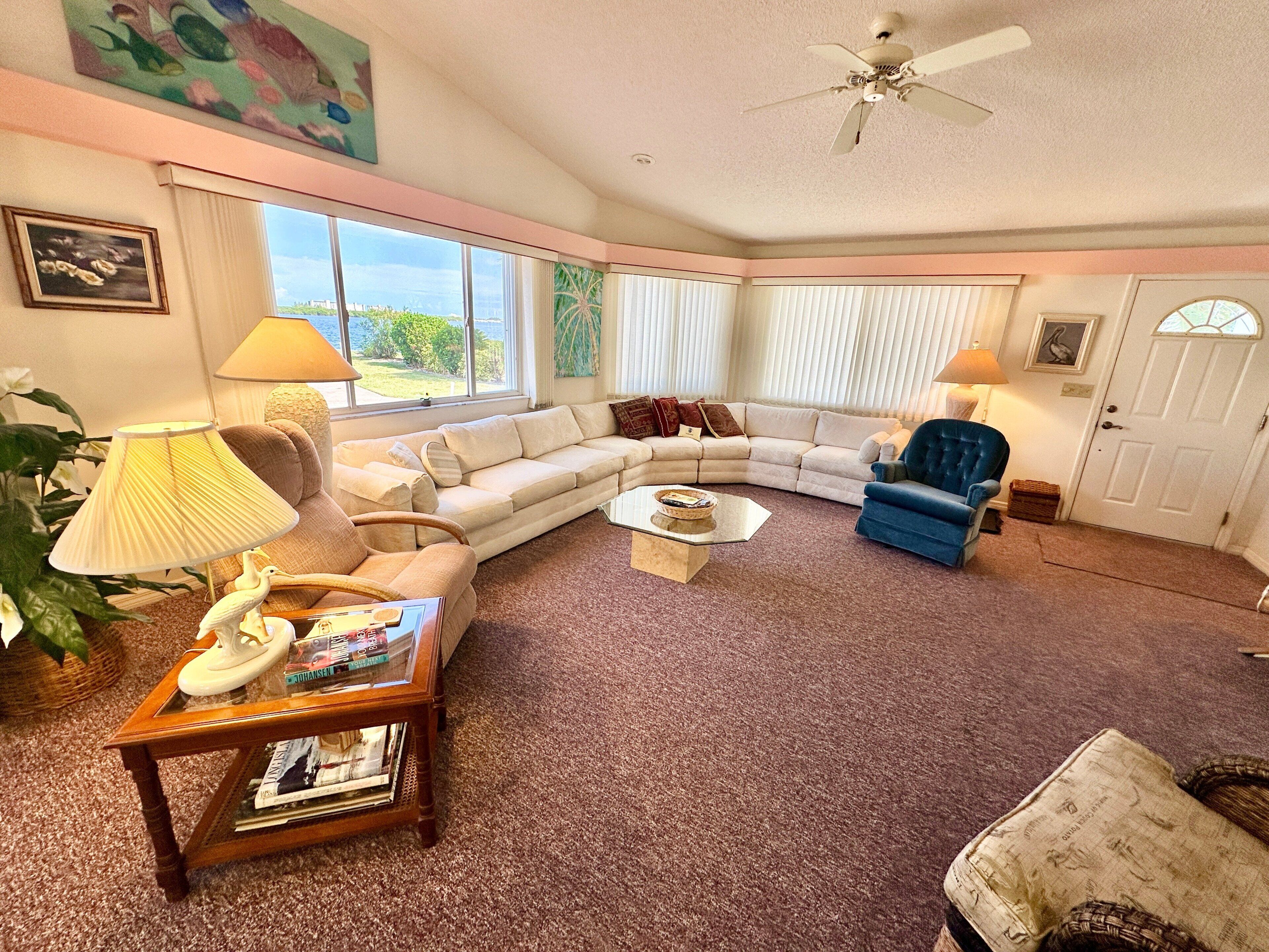 A living room with a sectional sofa, a blue armchair, a coffee table, and a ceiling fan.