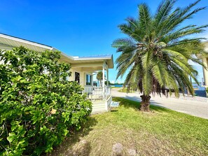 Ein Haus mit Veranda, einer Palme und einem 'For Sale'-Schild.