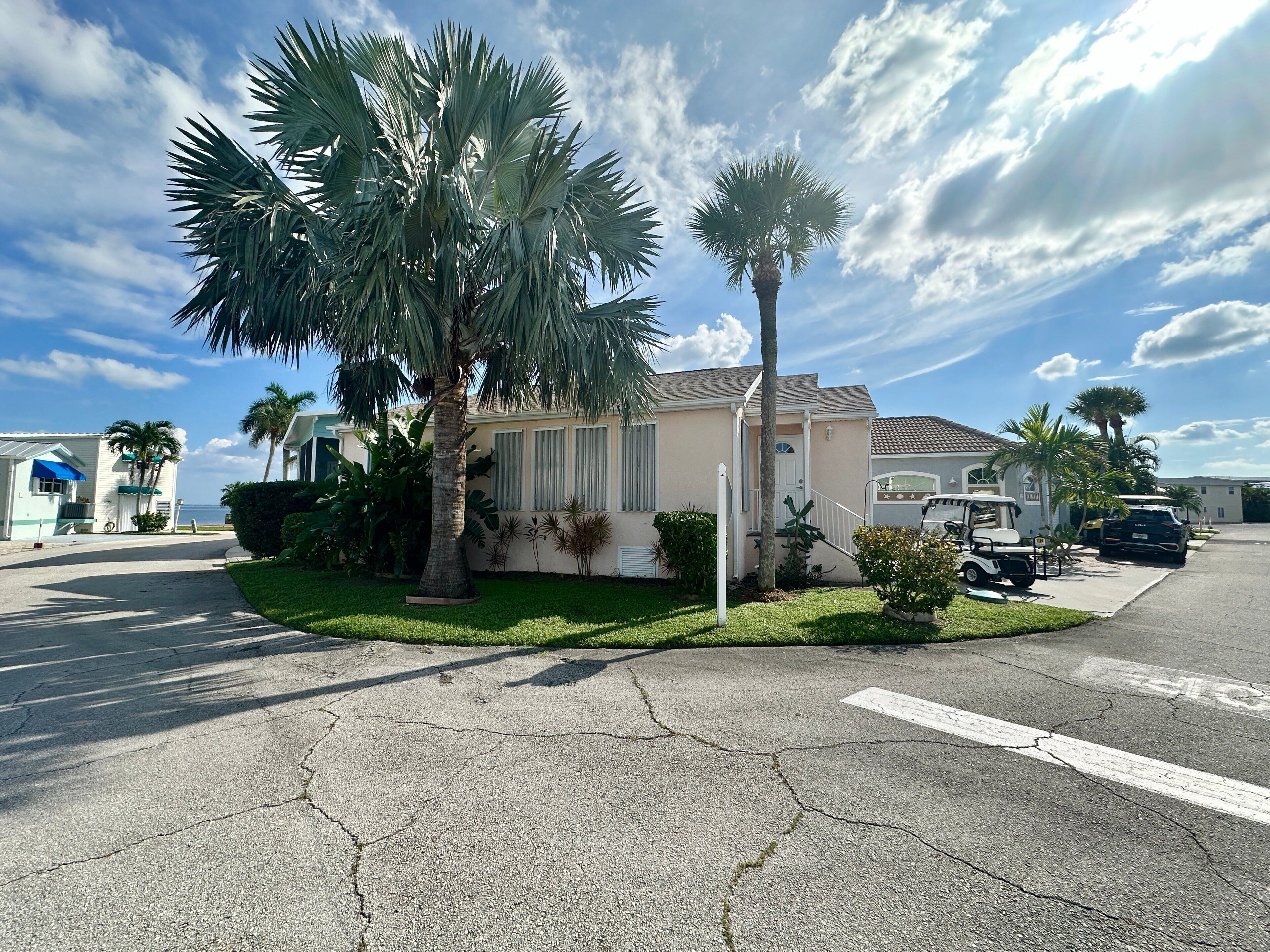 A residential area with a house, palm trees, and a golf cart.