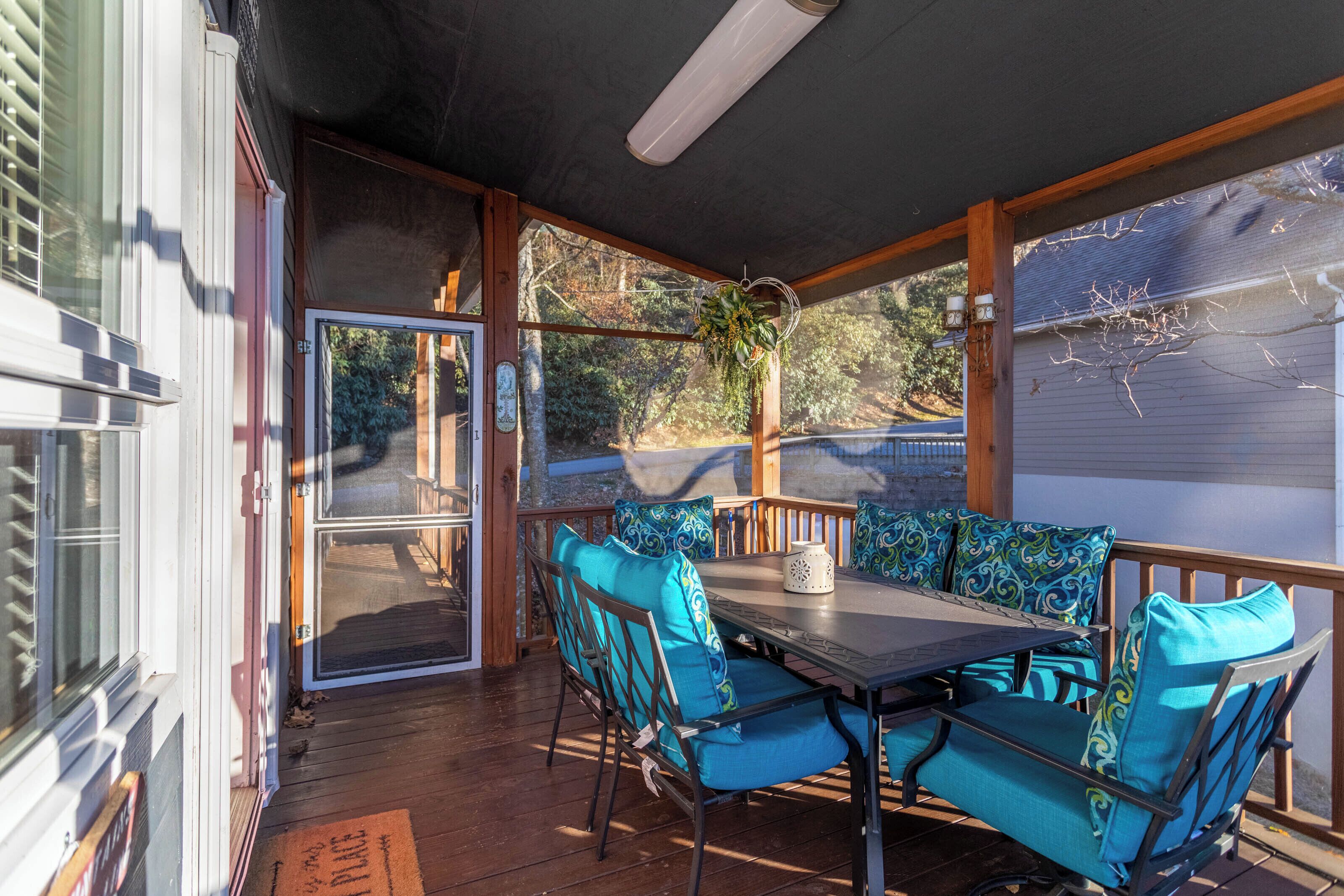 A covered patio with a table and chairs, a hanging plant, and a view of the outdoors.