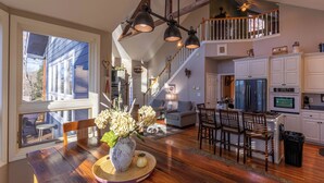 A spacious living area with a dining table, chairs, a staircase, and a kitchen with cabinets and appliances. - Misty Mountain Hideaway (Blowing Rock)