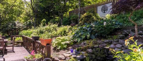 A wooden deck with outdoor furniture, a small garden with a pond, and a wooden fence.