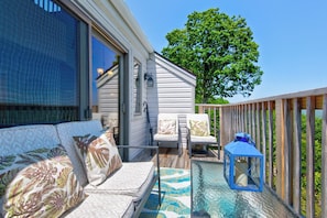 A deck with a sofa, two chairs, a table, and a lantern. - Top Of Seven 2BR - Amazing Grandfather Mtn Views From This Updated Condo (Banner Elk)