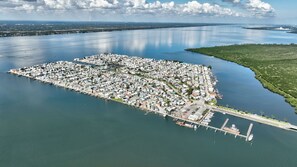 An aerial view of a coastal town with dense housing, a marina, and a bridge connecting to the mainland. - Beachbound 2BR Apt 1282 (Jensen Beach)