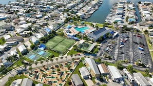 An aerial view of a residential area with a large swimming pool, tennis courts, and a marina. - Beachbound 2BR Apt 1282 (Jensen Beach)