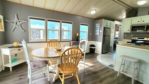 A kitchen with a dining area, wooden chairs, a star decoration, and a refrigerator. - Isle Always Luv View 2BR 1277 (Jensen Beach)