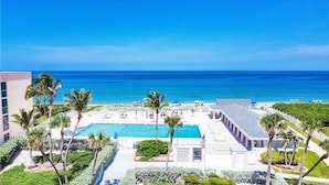 A resort with a pool, palm trees, and a view of the ocean. - Isle Always Luv View 2BR 1277 (Jensen Beach)
