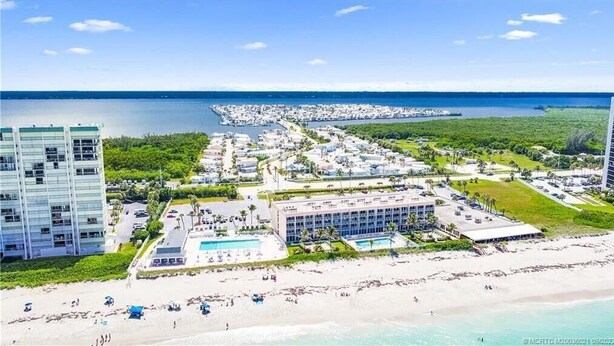 A coastal resort with a beach, a large pool, and multiple buildings. - Isle Always Luv View 2BR 1277 (Jensen Beach)