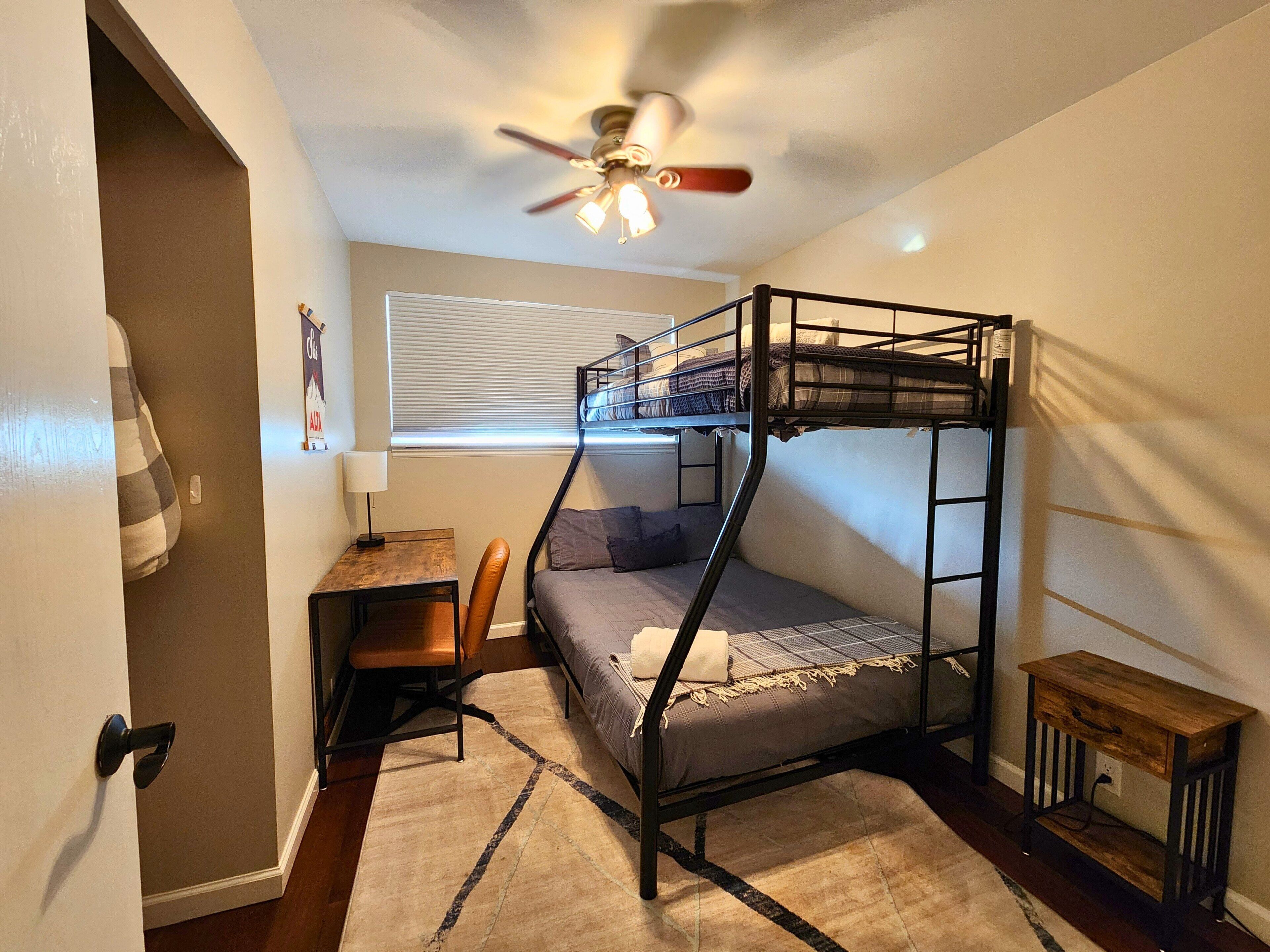 Habitación con literas, escritorio, silla y ventilador de techo.