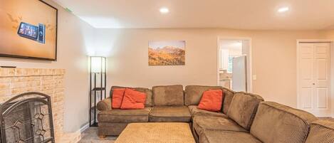 A living room with a sectional sofa, a fireplace, and a painting on the wall.