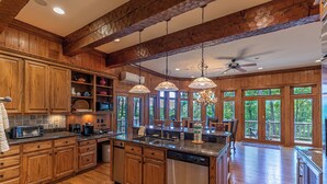 A spacious kitchen with wooden cabinets, a large island, and a view of the outdoors. - Amitola at Yonahlossee (Boone)